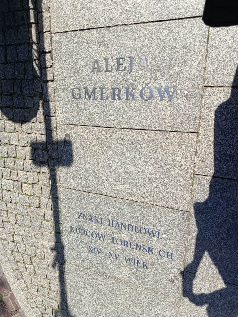 Napis w toruńskiej Alei Gmerków wskazuje znaki handlowe kupców z XIV i XV wieku – fot. Łukasz Augustyński